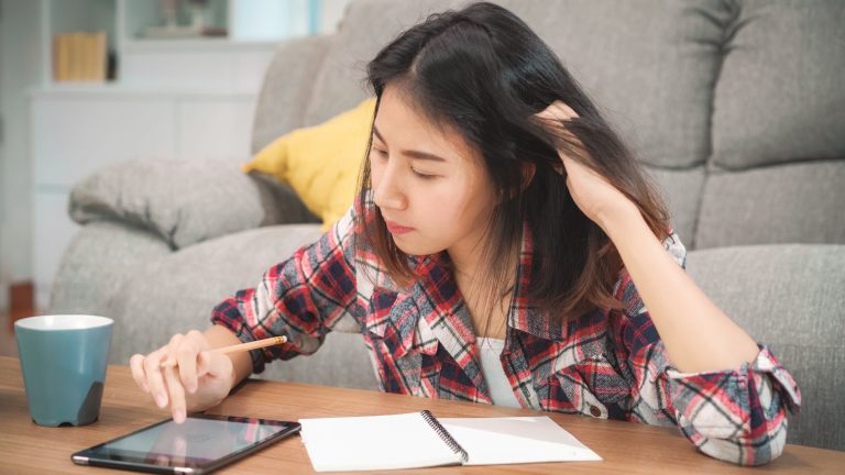 Student studying independently at home with digital resources during economic tuition, building understanding and exam readiness